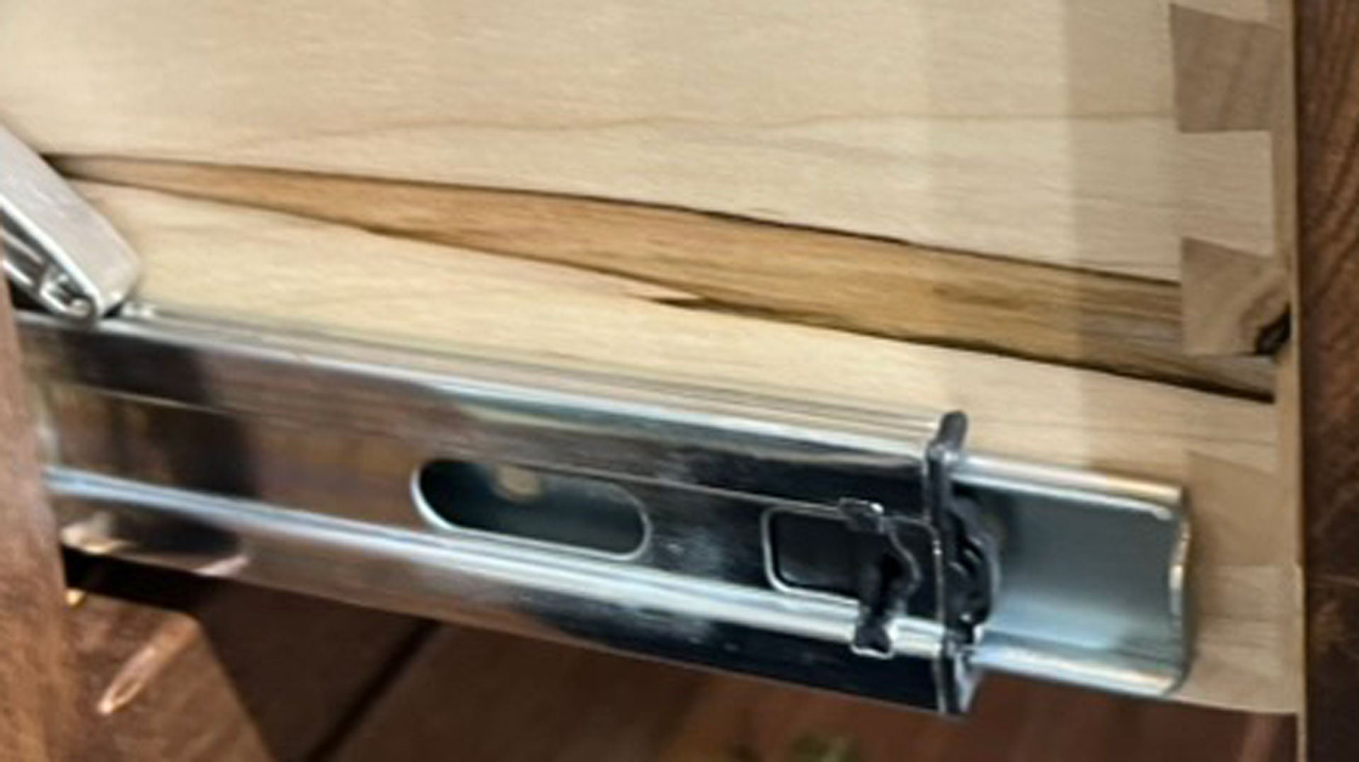 Guía metálica para cajones sobre una superficie de madera