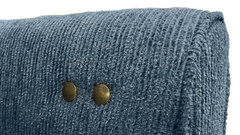 Close-up of a textured blue upholstered furniture corner with two brass nailhead accents on a white background.