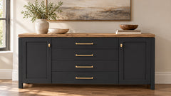 A dark charcoal sideboard cabinet with a light brown wood top, featuring four drawers with gold bar handles and two cabinet doors with small gold knobs. The cabinet is styled in a room setting with a vase of greenery, bowls, and a framed painting on the wall.