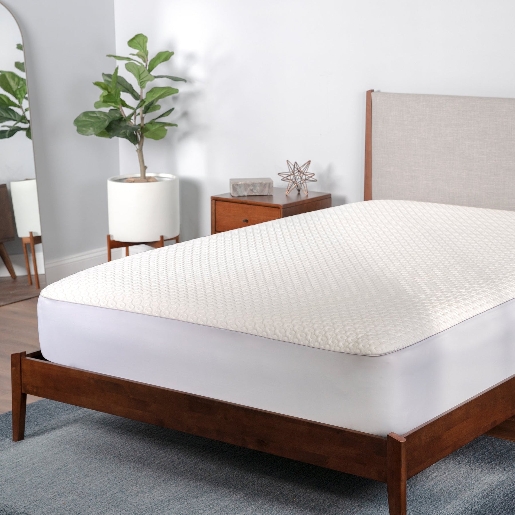 Mattress topper on a bed in a bedroom setting with plants and furniture.