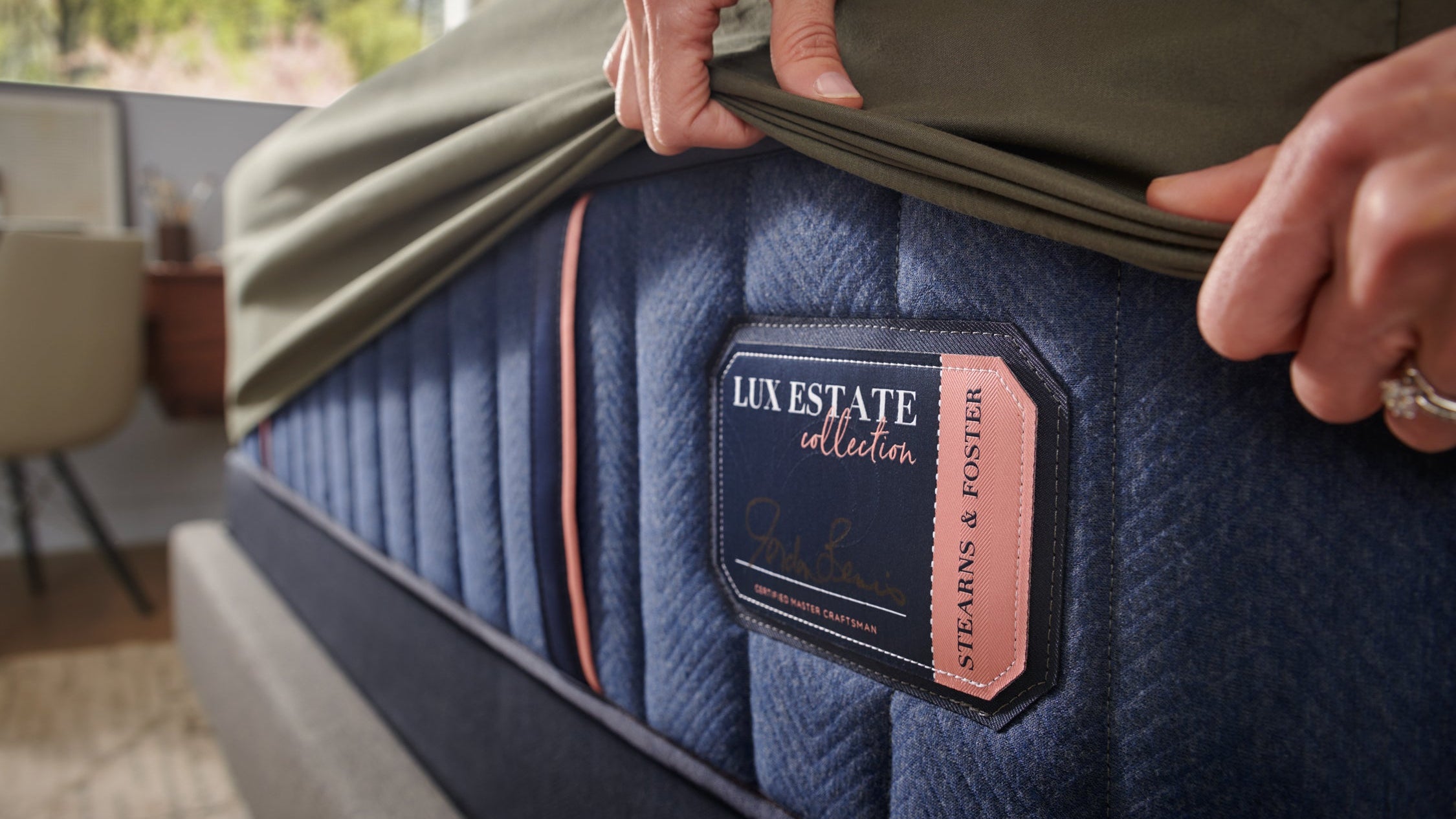 Lux Estate mattress with a hand holding the cover, showing the brand label.