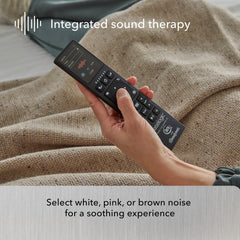 Hand holding a remote control with text about integrated sound therapy on a blurred background.