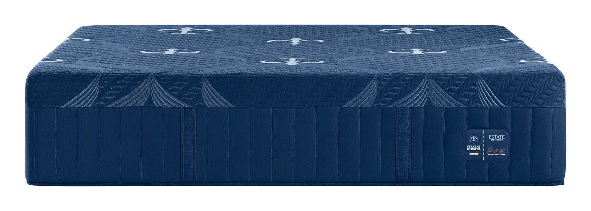 A dark blue mattress with a quilted top surface featuring a repeating anchor pattern and a ribbed side panel, shown on a plain white background. A small label on the side reads 'KESAGO' and 'FIRM'.