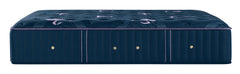 A luxury tufted mattress shown from a side profile view, featuring deep navy blue upholstery with purple piping accents and gold button details.