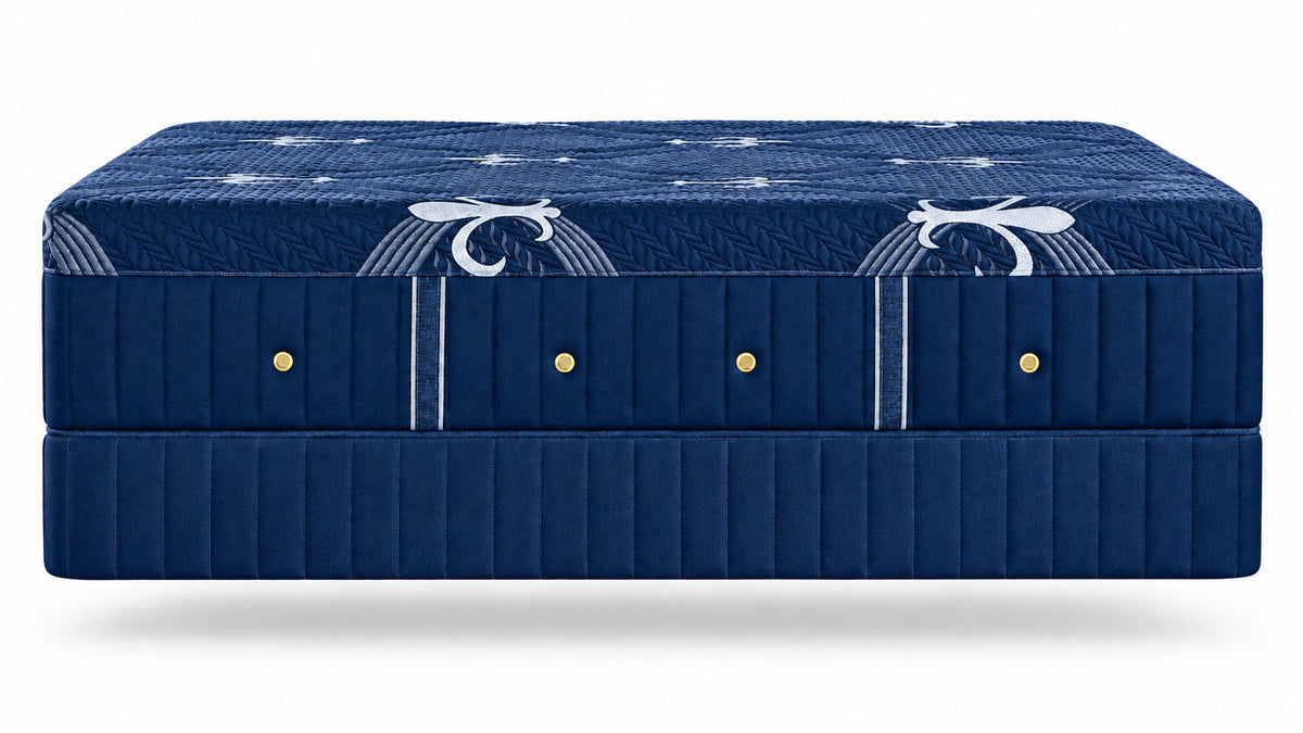 A dark blue upholstered bed frame or mattress base with decorative white scroll motifs and small gold button accents, shown against a plain white background.