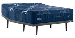 A Stearns & Foster mattress on a black metal bed frame, shown from a three-quarters angle against a solid white background.