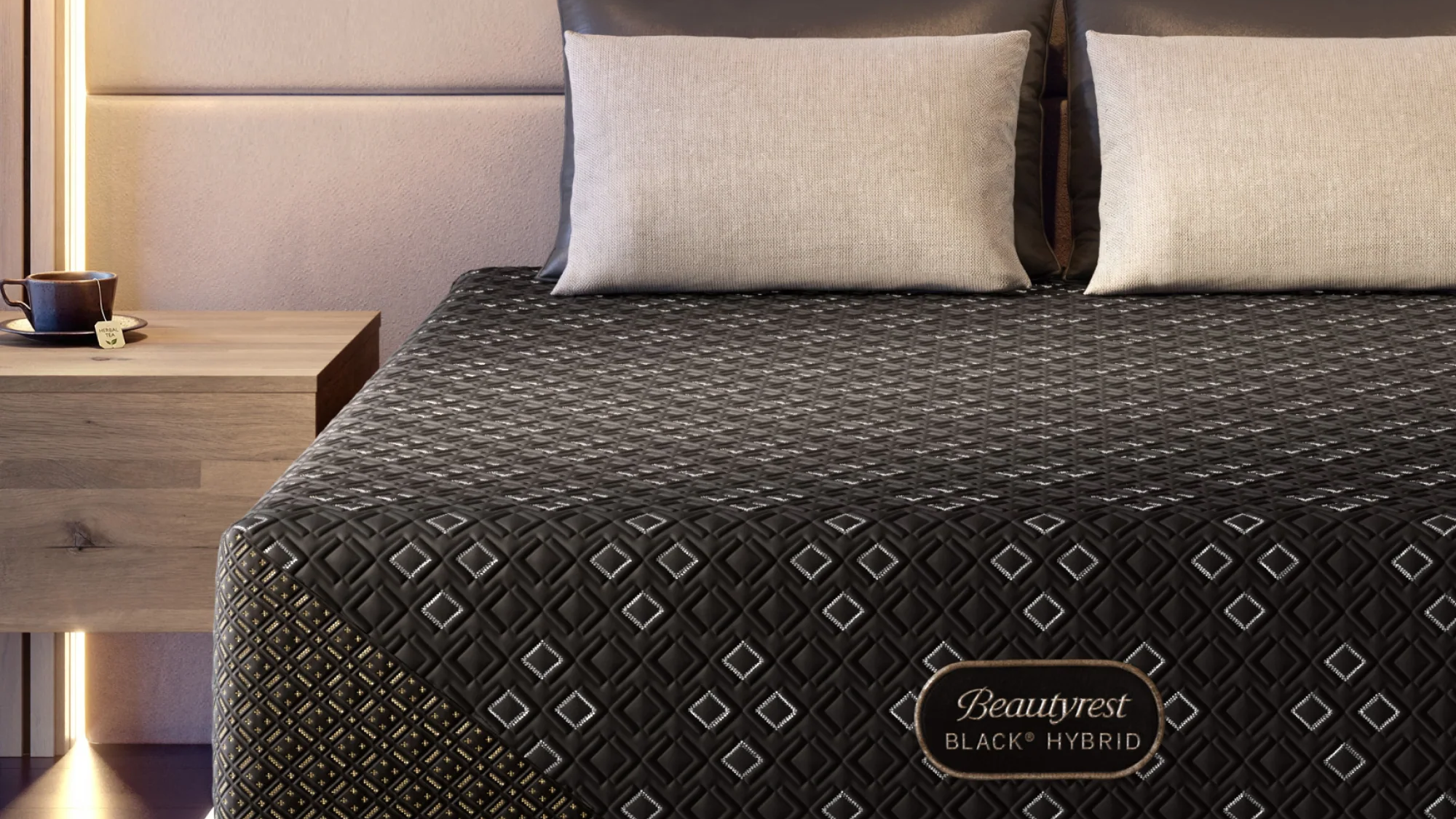 Black hybrid mattress on a bed with beige pillows in a modern bedroom setting.