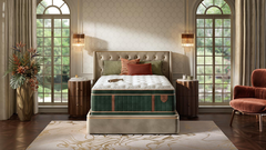 A luxury mattress in a tufted bed frame, styled in a beautifully decorated bedroom with two tall arched windows, bedside tables, lamps, and a plush armchair.