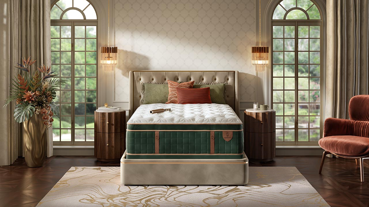 A luxury mattress in a tufted bed frame, styled in a beautifully decorated bedroom with two tall arched windows, bedside tables, lamps, and a plush armchair.