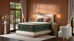 A luxury mattress shown in a fully styled, elegant bedroom setting with warm terracotta walls, a white upholstered headboard, a green and brown mattress, and matching pillows.
