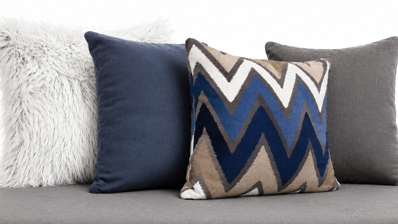 Set of decorative pillows on a sofa including a zigzag pattern pillow.