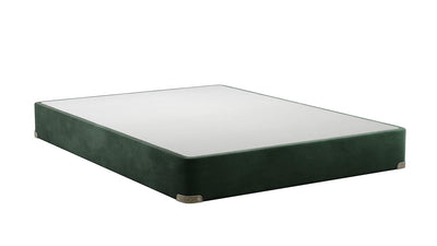 Un somier tapizado de color verde oscuro o una cama de plataforma con un colchón blanco, fotografiados en ángulo sobre un fondo blanco liso.