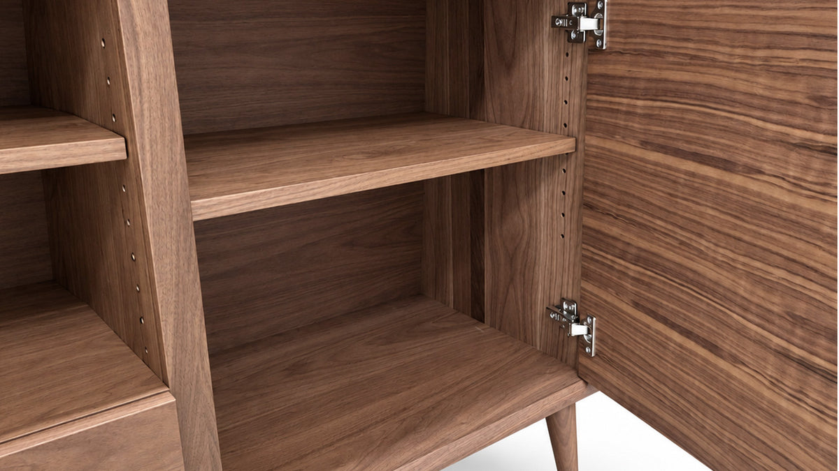 Close-up of a wooden storage cabinet or bookshelf with an open door, showing three interior shelves and metal hinges against a white background.