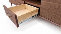 A close-up of a wooden cabinet with one drawer pulled open, showing a light natural wood drawer interior and metal drawer slides against a white background.