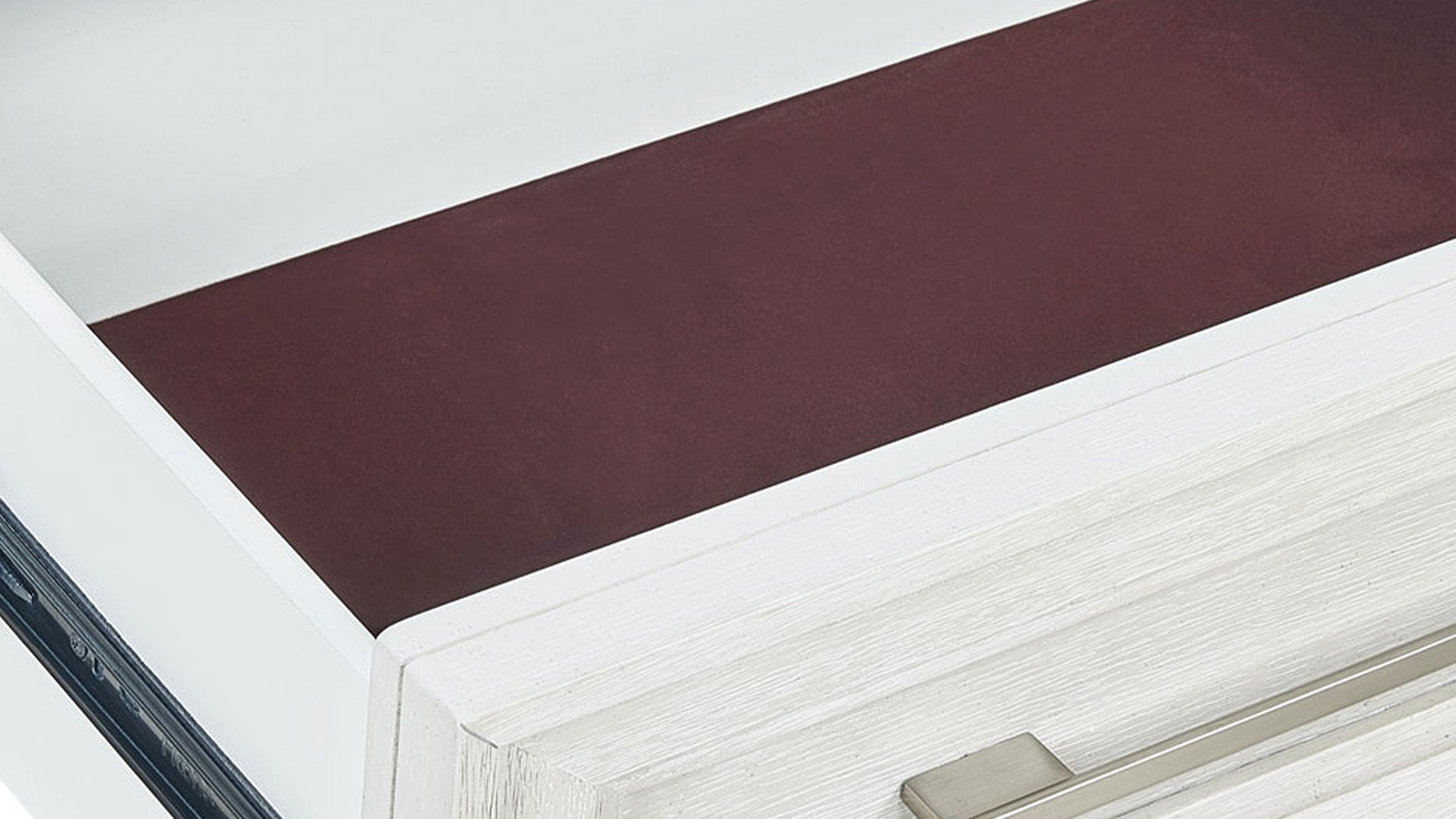 Primer plano de un cajón blanco con un tapete marrón oscuro en su interior