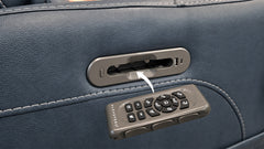 Close-up of a dark blue leather seat or chair with a metallic control panel and a matching remote control attached or resting on the surface.