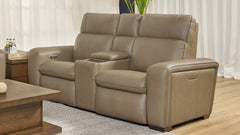 Sofá de cuero beige en un salón con una mesa de centro de madera y cortinas.