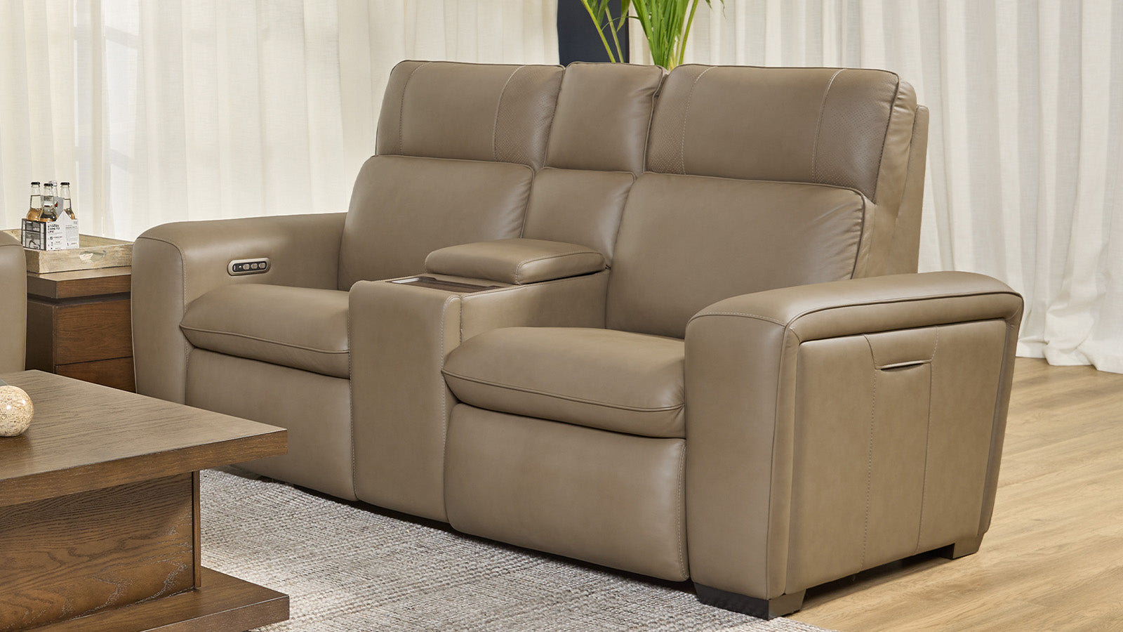 Sofá de cuero beige en un salón con una mesa de centro de madera y cortinas.