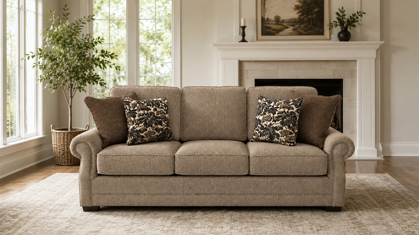 Beige sofa with patterned pillows in a living room setting with a fireplace and windows.