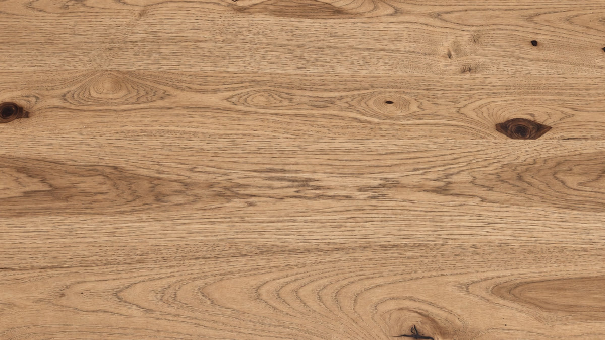 A close-up of a natural wood surface with visible grain, knots, and warm tan-brown tones.